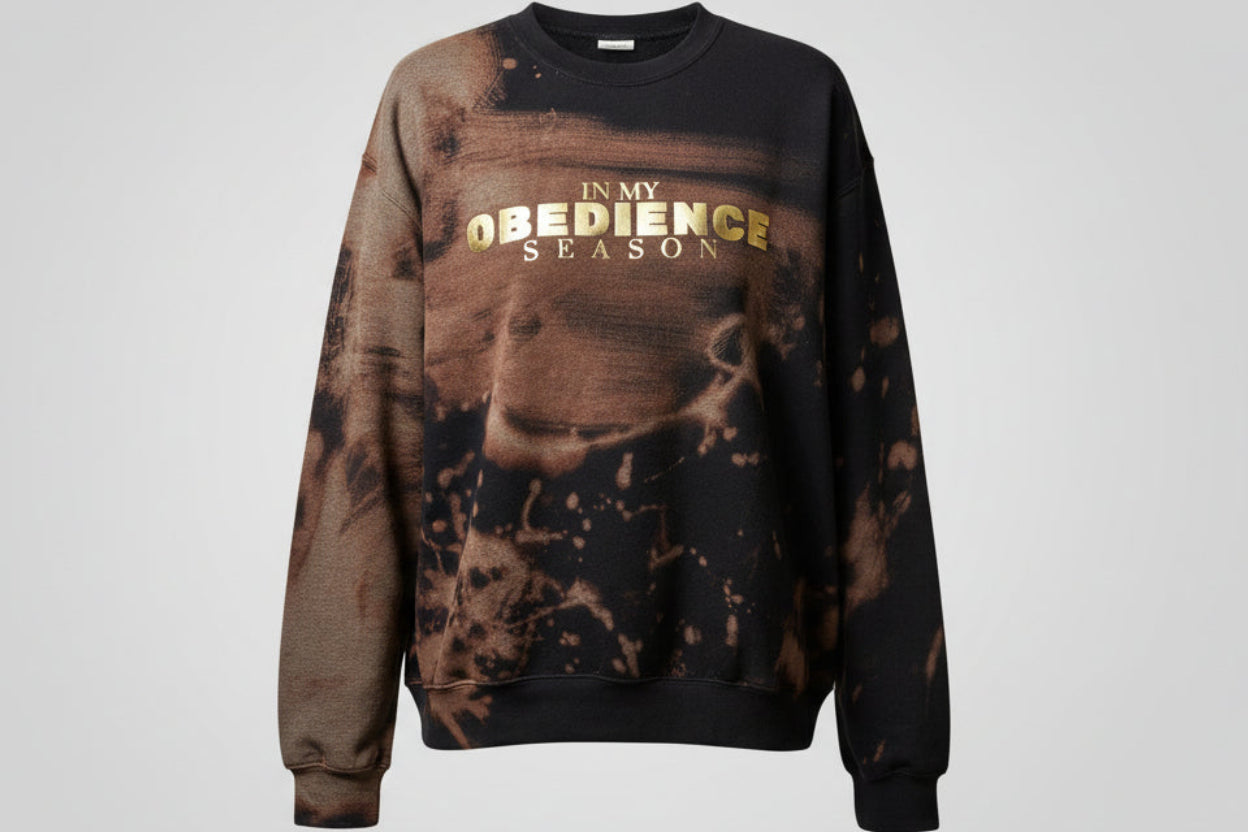 Person wearing a crew neck with text, standing indoors.